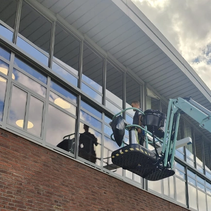 Plaatsing van zonwerende raamfolie aan buitenzijde van kantoorgebouw H-Vest met hoogwerker