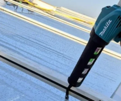 "Professionele afdichting van glasconstructie tijdens montage van raamfolie met Makita kitpistool"