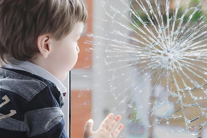 Kind bij raam met veiligheidsfolie die glassplinters tegenhoudt na impact